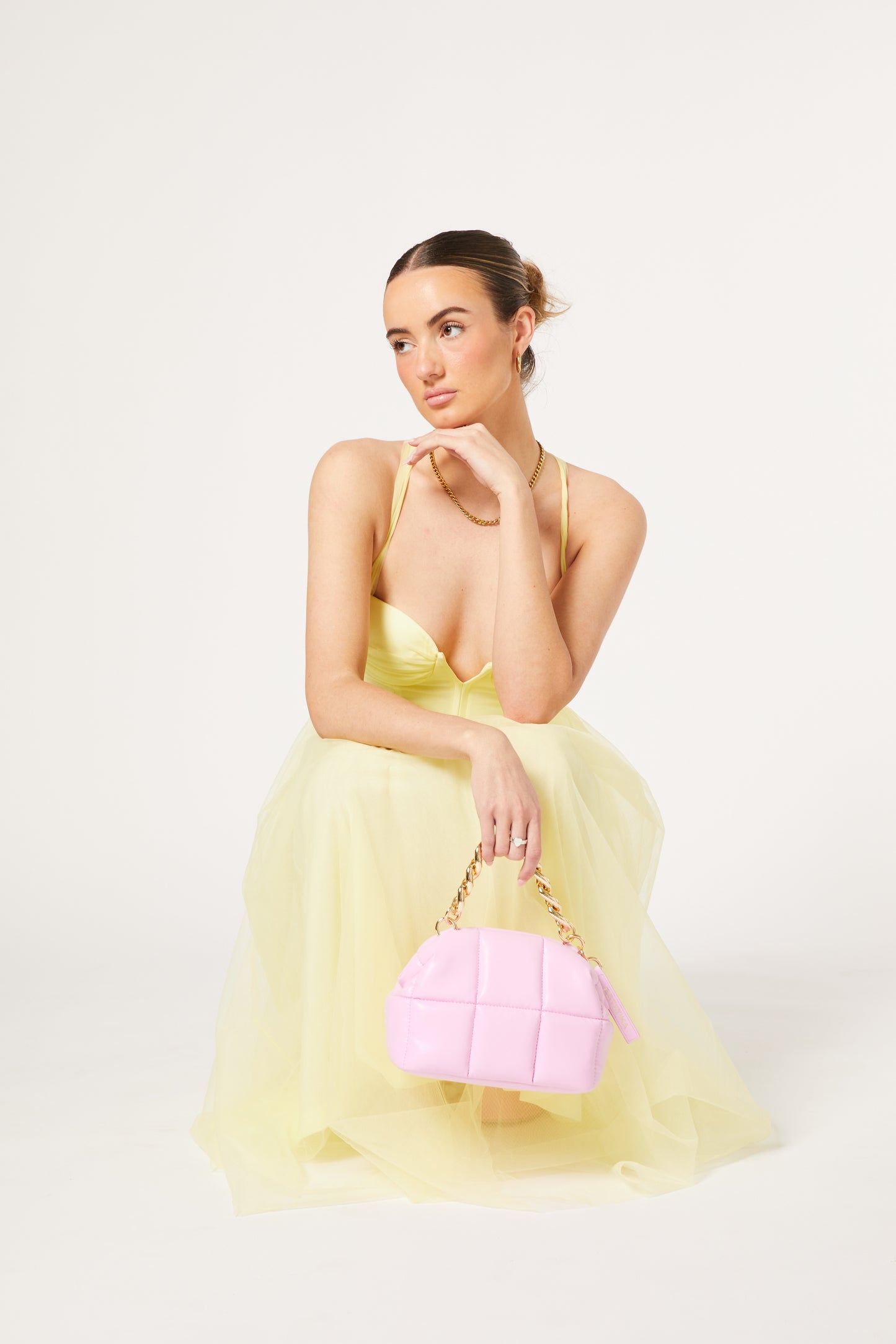 Model holding pink makeup clutch bag in a yellow dress